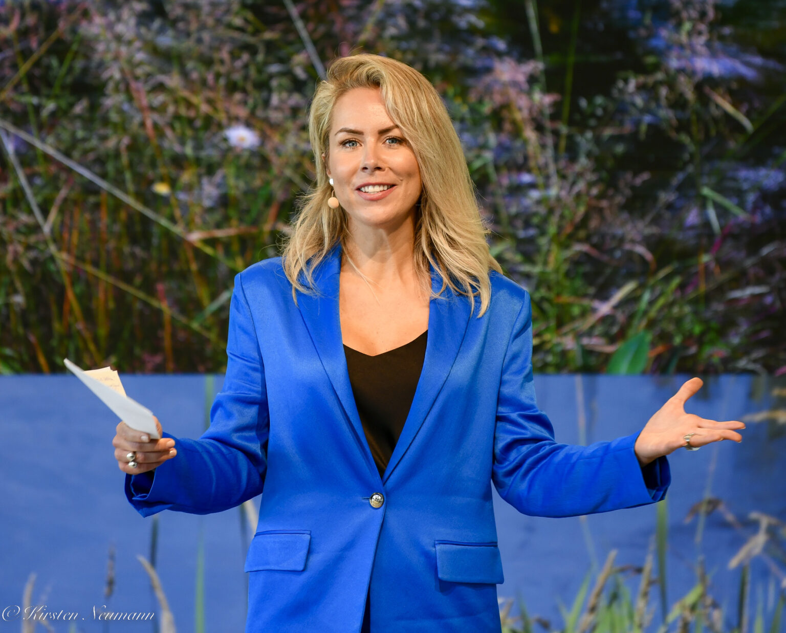 Dr. Ines Marbach im blauen Anzug mit offener Geste und Moderationskarten